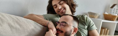 Eşcinsel bir çift kanepede sarılır, birbirlerine eşlik etmekten zevk alırlar..
