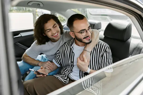 stock image A gay couple smiles and embraces in the backseat of a car.