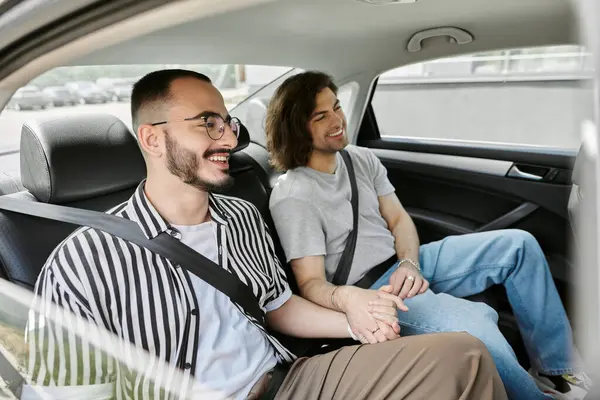 stock image A gay couple smiles and holds hands while riding in a car.