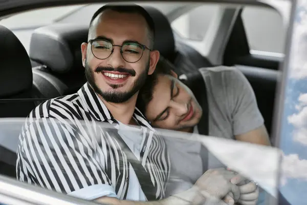 stock image Happy gay couple in car, one looking out window, other resting head on partner's shoulder