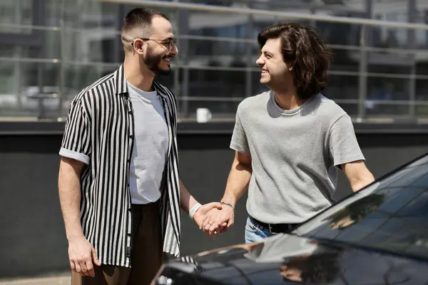 stock image A loving gay couple holds hands and smiles while walking by a car.