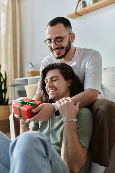 stock image A man surprises his partner with a gift, both beaming with joy.