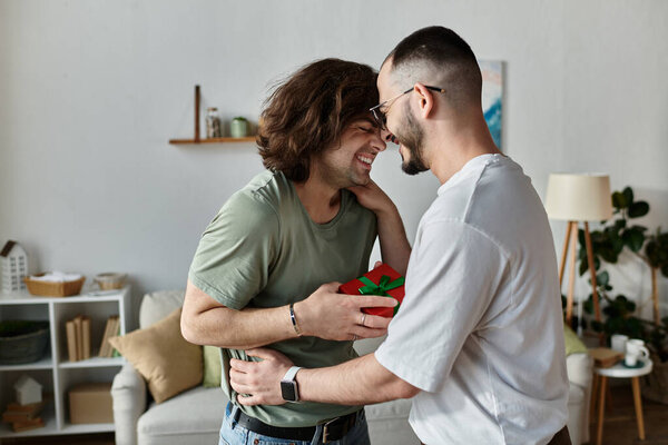 A gay couple shares a tender moment, one holding a wrapped gift.