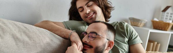 A gay couple cuddles on a couch, enjoying each other's company.
