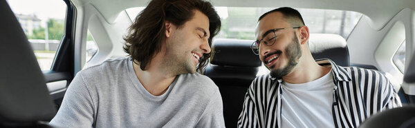 Двое мужчин смеются вместе на заднем сидении машины.