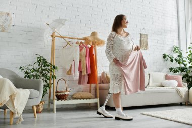 A young woman with a prosthetic leg stands in her home, smiling as she chooses an outfit from her closet. clipart