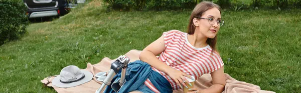 stock image A young woman with a prosthetic leg relaxes on a blanket in a grassy park, enjoying a sunny day.