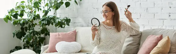 stock image A young woman applies makeup in her home, showcasing self-care and confidence.