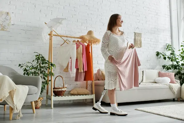 stock image A young woman with a prosthetic leg stands in her home, smiling as she chooses an outfit from her closet.