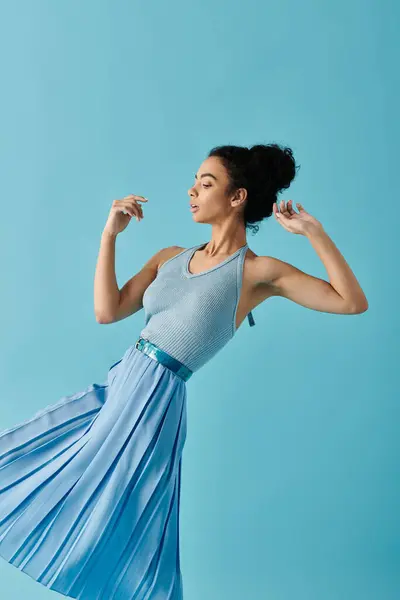 stock image A young woman in a blue dress poses against a vibrant blue background.