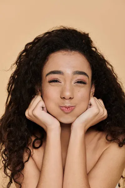 stock image A young woman with curly hair rests her chin on her hands, her eyes closed in thoughtfulness.