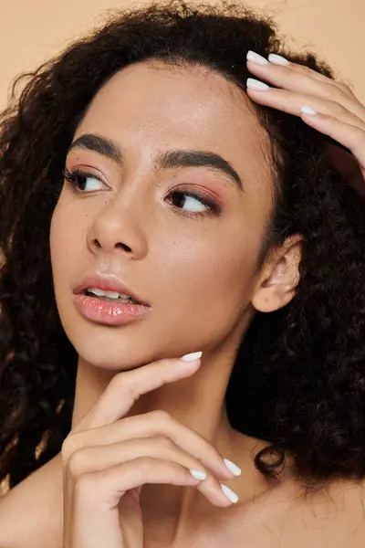 Stock image A young woman with curly hair gazes thoughtfully, showcasing natural beauty and a confident expression.