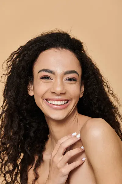 stock image A young woman with curly hair and a bright smile looks directly at the camera, showcasing natural beauty and confidence.