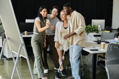 Dört meslektaş bir ofiste toplanıyor, gülümsüyor ve akıllı bir telefonla fotoğraf çekiyorlar..