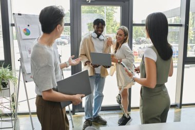 Bir grup genç profesyonel modern bir ofiste bir projeyi tartışıyor..