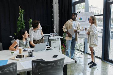 Yeni başlayan bir proje üzerinde çalışan dört meslektaşı modern bir ofis ortamında işbirliği yapıyor..