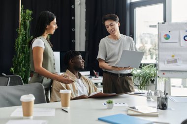 Bir konferans masasının etrafında üç iş arkadaşı beyin fırtınası yapıyor..