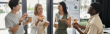 Dört meslektaş, modern bir ofiste pizza ve kahveyi paylaşarak kısa bir öğle yemeği arası veriyor..