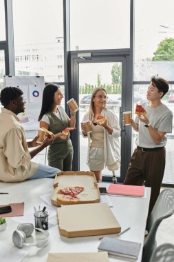 Dört iş arkadaşından oluşan bir grup, ofiste mola sırasında pizza ve içkinin keyfini çıkarıyor..