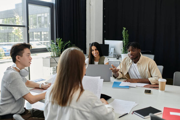 Four colleagues gather around a table, discussing a project idea.
