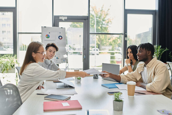 Группа молодых профессионалов работает вместе над планом запуска в ярко освещенном офисе.