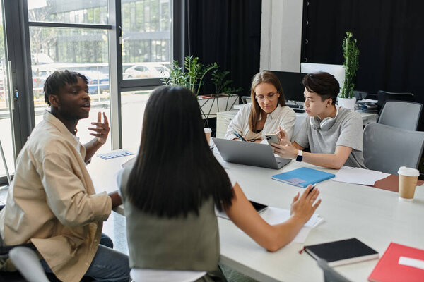 Четыре человека работают над идеей создания стартапов за столом в современном офисе.