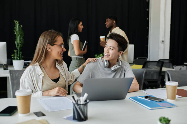 Two colleagues discuss ideas at a modern office desk.
