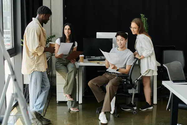 Stock image Four colleagues review documents in a contemporary office setting.