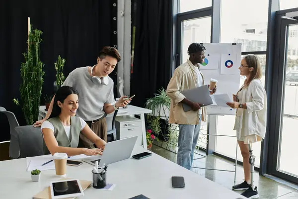 stock image Four coworkers discuss a project, with one person working on a laptop.