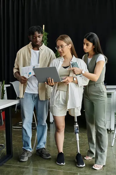 stock image Three colleagues collaborate on a laptop while looking at documents.