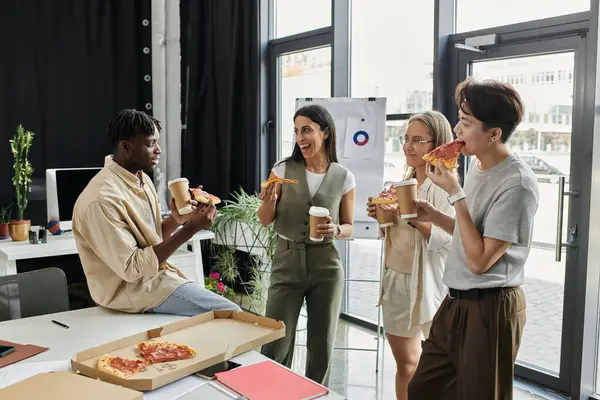 stock image A group of four colleagues enjoys a pizza and coffee break in a contemporary office setting.