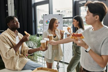 Dört meslektaş, modern bir ofiste mola verirken pizza ve kahveden hoşlanırlar..