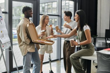 Dört meslektaş, modern bir ofiste pizza ve kahvenin tadını çıkarmak için işe ara veriyor..