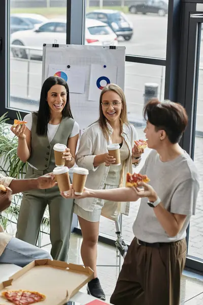 Bir grup yeni başlayan iş arkadaşı, pizza ve kahvenin tadını çıkarmak için ofislerinde mola veriyor..