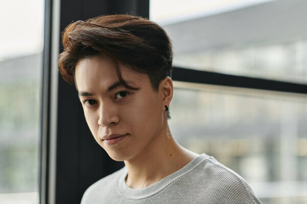 Young man in grey shirt focused on camera with determination