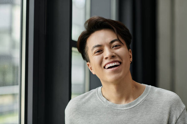 A young man smiles at the camera while working on a startup.