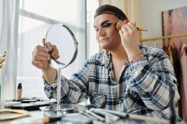 Ekose gömlekli bir eşcinsel aynaya bakarken makyaj yapar..