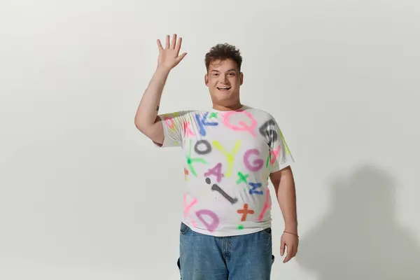 stock image A queer person in a bright, colorful shirt smiles and waves, exuding confidence and joy.