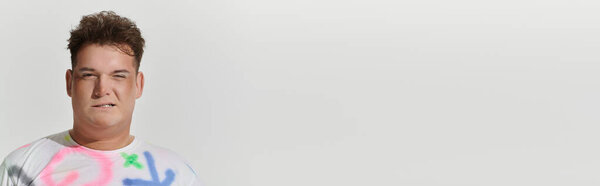 A young queer person poses against a white backdrop.