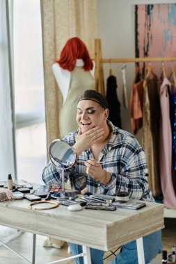 Eşcinsel insan güzellik ürünleri arasında aynaya makyaj yapar.