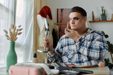 Eşcinsel adam makyaj yapar, parlak odadaki yansımaya odaklanır.