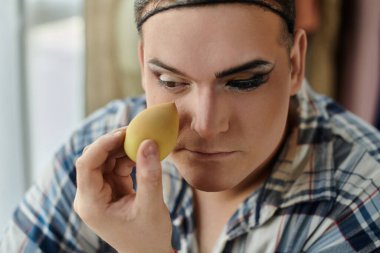 İbne biri makyajını süngerle yapar, göz makyajına odaklanır..