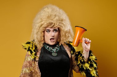 Sarı ve siyah kıyafetli tuhaf bir insan sarı arka planda bir megafon tutuyor..