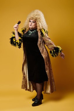 Leopar desenli ceketli ve siyah elbiseli bir travesti mikrofon tutuyor ve şarkı söylüyor..