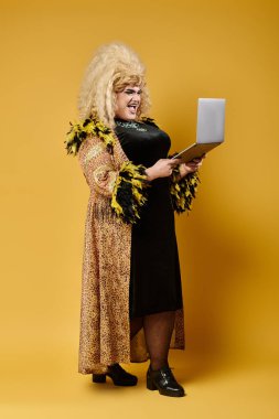 Leopar desenli ceketli ve siyah elbiseli bir travesti dizüstü bilgisayarla poz veriyor..