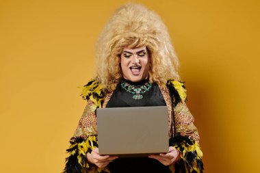 Muhteşem giyinmiş bir travesti dizüstü bilgisayar kullanırken gülümsüyor..