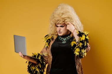 Siyah bluzlu şık bir travesti dizüstü bilgisayar tutuyor, kafası karışmış görünüyor.