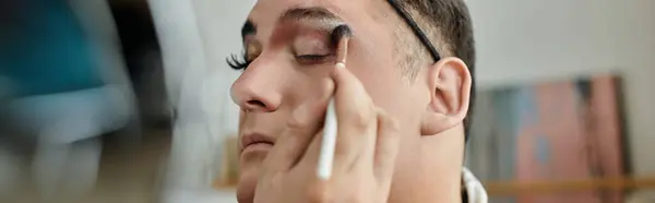 stock image A queer person applying eye makeup with a brush.