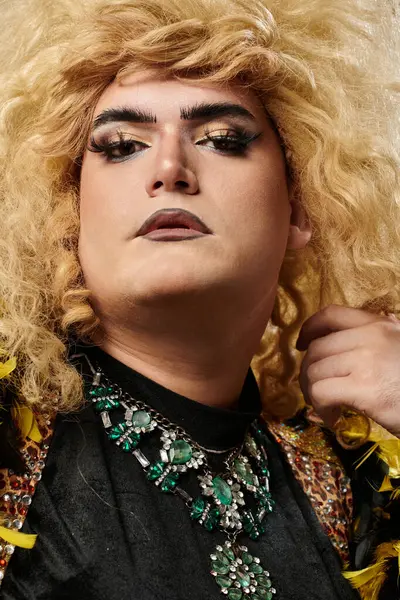 stock image A queer person with blonde curls and bold makeup stares intensely at the camera.