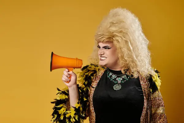 stock image Stylish queer person in feathered jacket yells through megaphone on yellow background